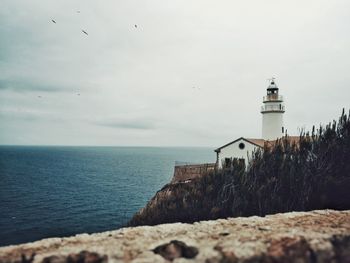 Lighthouse by sea against sky