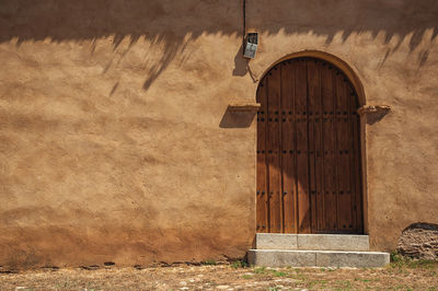 Wooden closed door on a rough plaster wall in an old house at the monfrague national park, in spain.