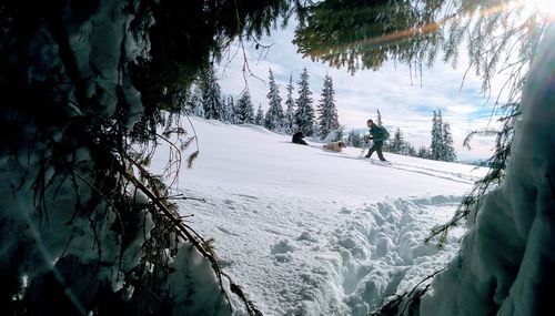 Side view of mature man skiing on snow covered landscape against sky