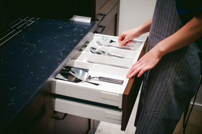 Midsection of woman holding eating utensils at kitchen