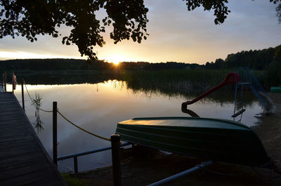 Boat with slide by lake against cloudy sky