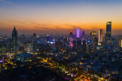 Illuminated cityscape against sky during sunset