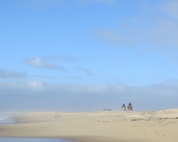 People walking on beach against sky