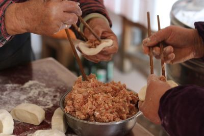 Cropped hands of people preparing food using chopsticks