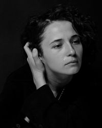 Portrait of young woman against black background