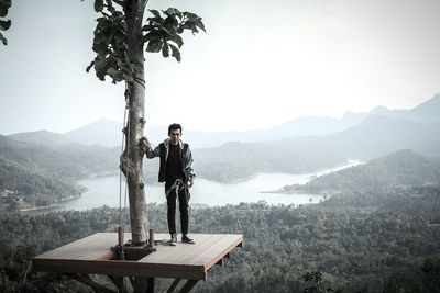 Portrait of man with safety harness standing against mountain range