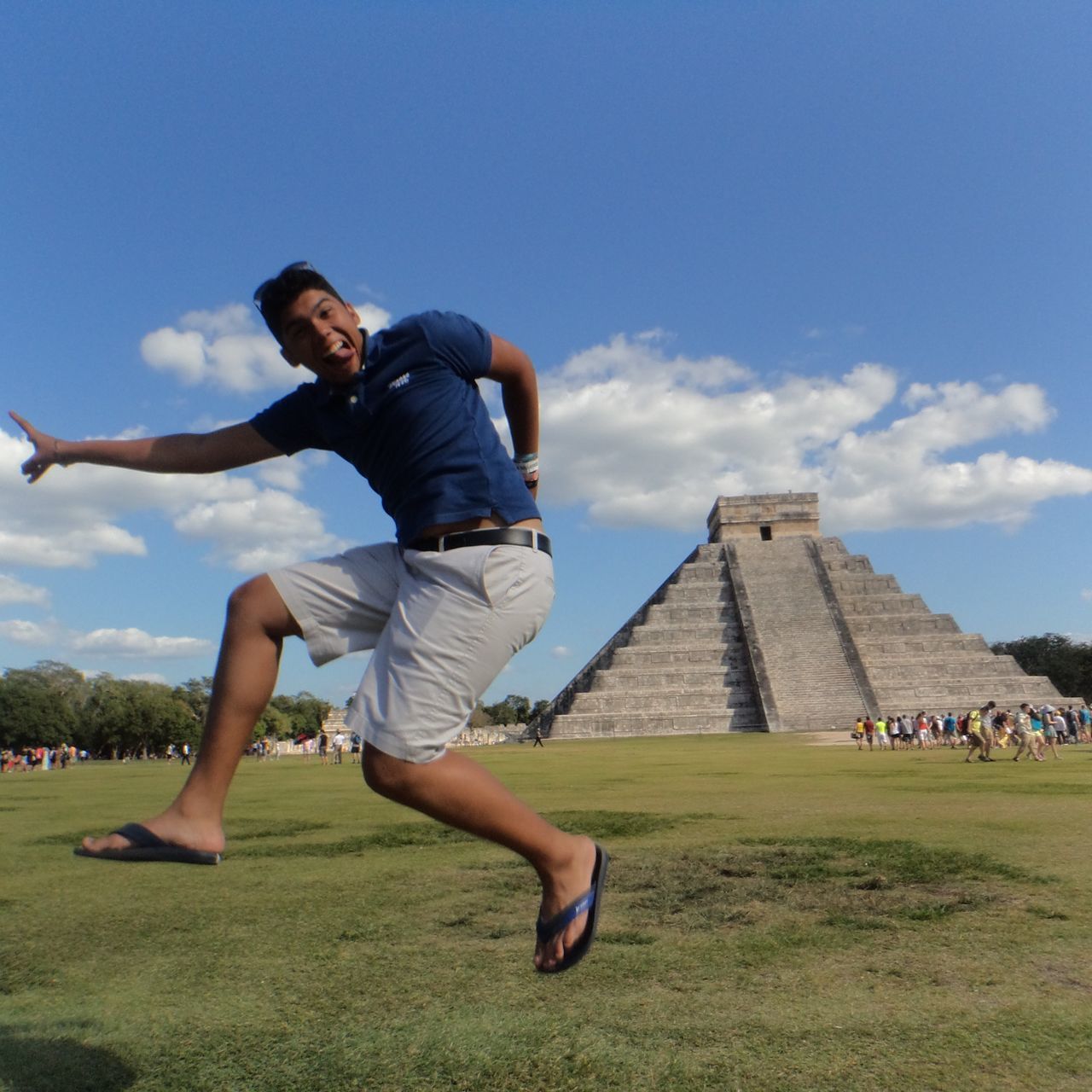 full length, lifestyles, leisure activity, casual clothing, building exterior, architecture, built structure, person, grass, young adult, mid-air, sky, jumping, young men, fun, low angle view, arms outstretched, enjoyment