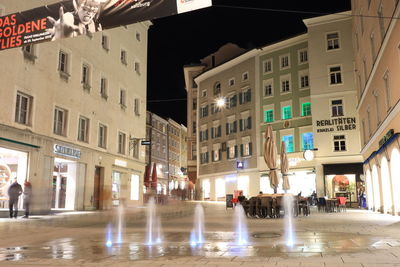 People on street amidst buildings in city at night