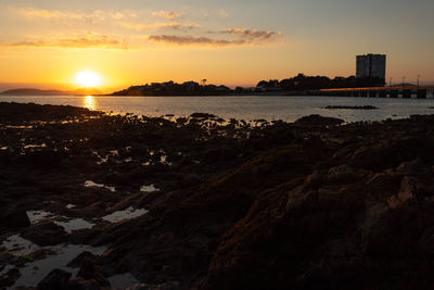Scenic view of sea and buildings against sky during sunset