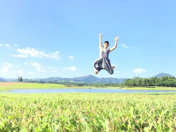 Full length of man jumping on field against sky