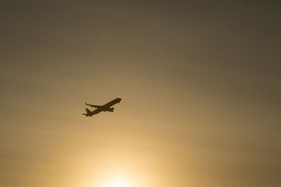 Low angle view of silhouette airplane against sky during sunset