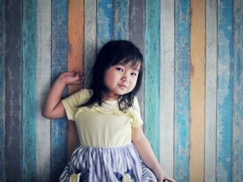 Portrait of smiling girl against wooden wall