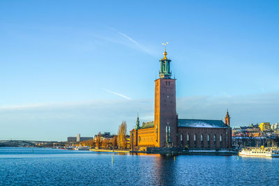 Buildings by river against clear sky