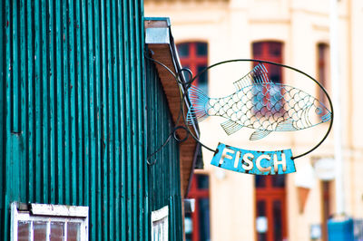 Low angle view of metallic fish sign on wall in city