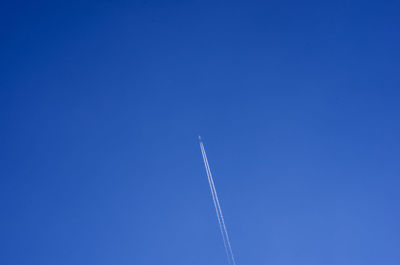 Low angle view of vapor trail against blue sky