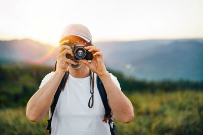 Man taking photos on mountain at sunset