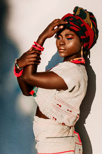 Sunlight falling on woman posing by white wall