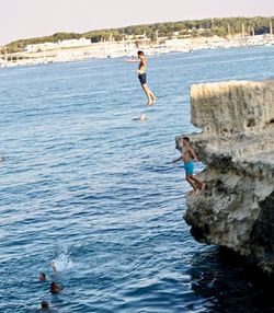 Man jumping on rock in sea