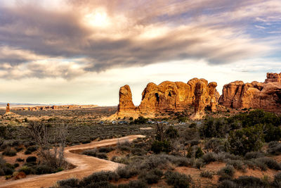 Rock formations on landscape against cloudy sky