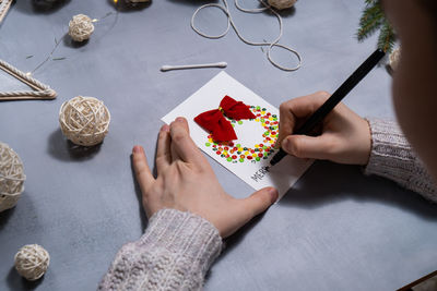 Cropped hand of woman painting on table