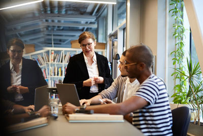 Male entrepreneurs giving presentation to female bank manager over laptop at desk in creative office