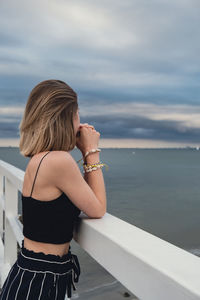 Young woman standing on wooden pier blurred beachside background. attractive female enjoying the sea