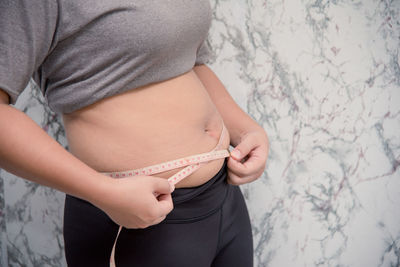 Midsection of woman standing against wall