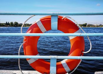 Bright orange life buoy on the pier of pleasure boats and boats on a sunny summer day.