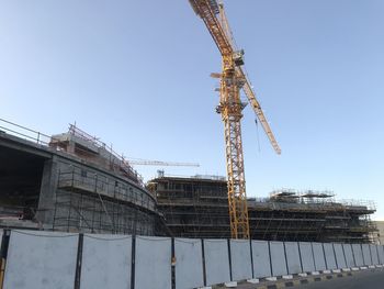 Low angle view of crane at construction site against sky