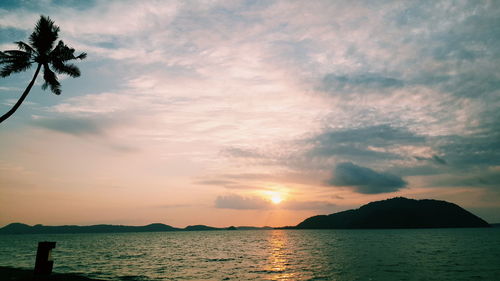 Scenic view of sea against cloudy sky during sunrise