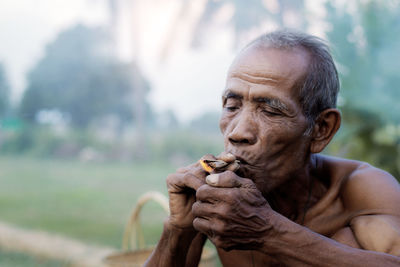 Shirtless man smoking while sitting outdoors