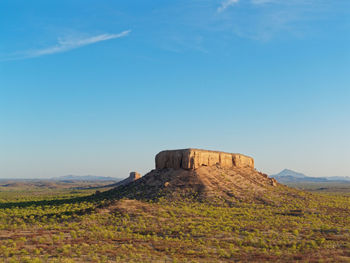 Rock formations on landscape against blue sky