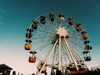 Low angle view of ferris wheel against blue sky