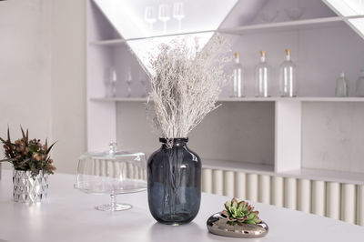 Glass vase and decorative floral elements on a white table