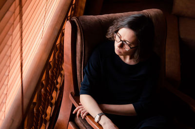 A portrait of a girl sitting in a chair close to the window shot from the high point of view