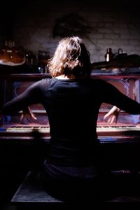 Rear view of woman sitting on table