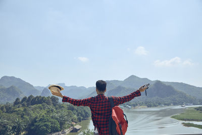 Rear view of man standing on mountain against sky