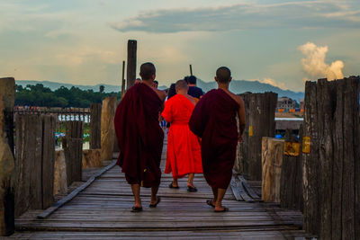 Rear view of people walking on cross against sky