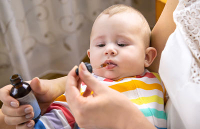 Mother feeding medicine to baby at home