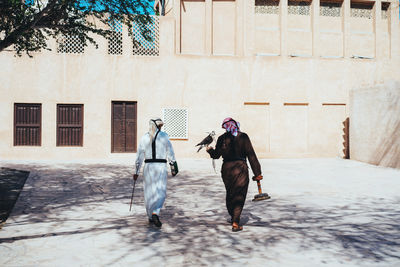 Rear view of people walking on street against building