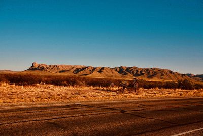 Scenic view of arid landscape against clear blue sky