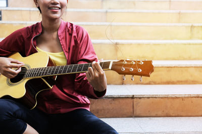 Midsection of man playing guitar