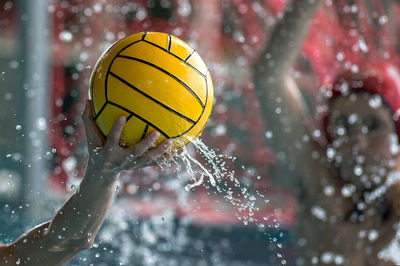 Close-up of hand holding ball with water splashing