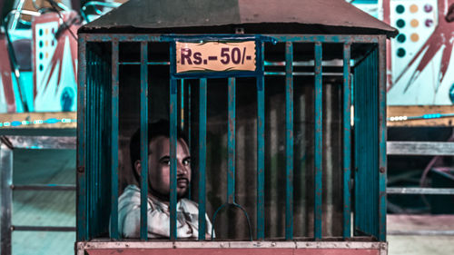 Portrait of man sitting in cage