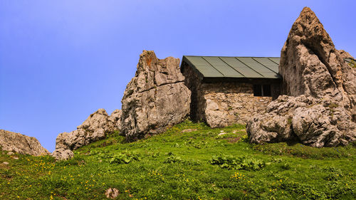 House on rock against clear blue sky