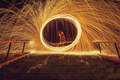 Blurred motion of man standing by illuminated light at night