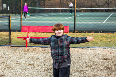 Portrait of boy with arms outstretched standing on playground