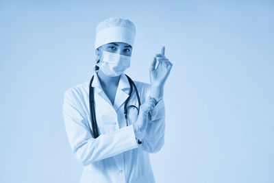 Portrait of doctor standing against blue background