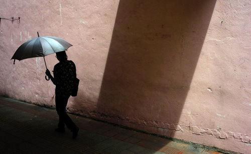 Woman with umbrella standing on tiled floor