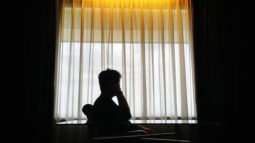 Side view of silhouette woman sitting at home